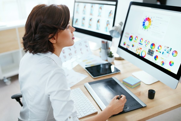 A person sits at a computer and reviews logo color theory.