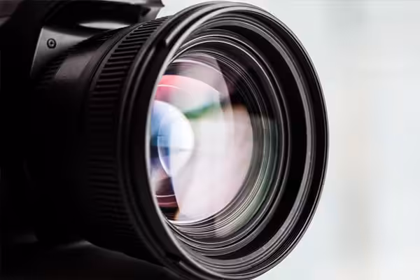 A closeup of a camera lens reflecting a prismatic color.