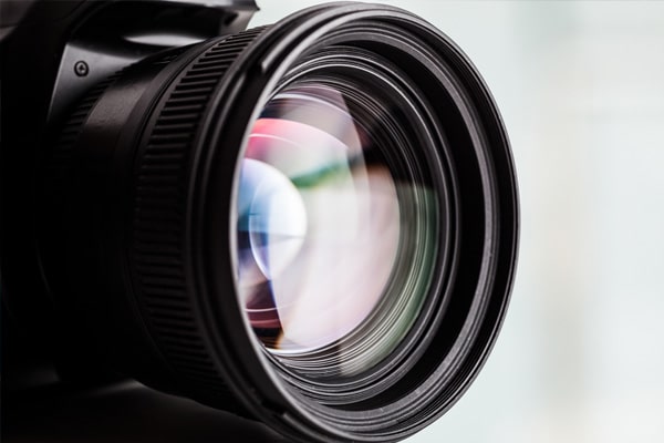 A closeup of a camera lens reflecting a prismatic color.