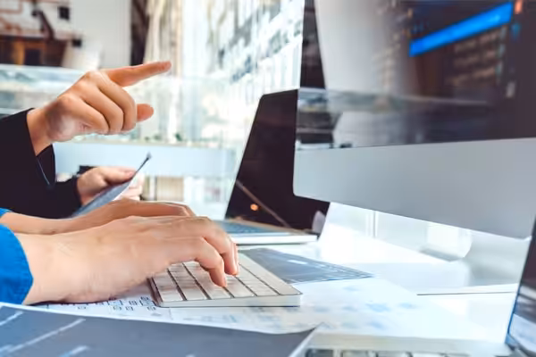 Two people work together at a computer researching SEO keywords.