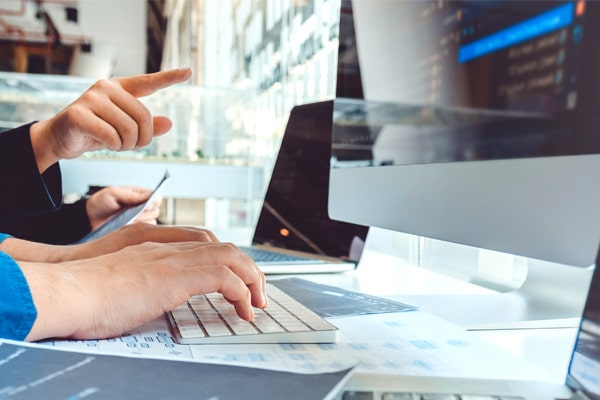 Two people work together at a computer researching SEO keywords.