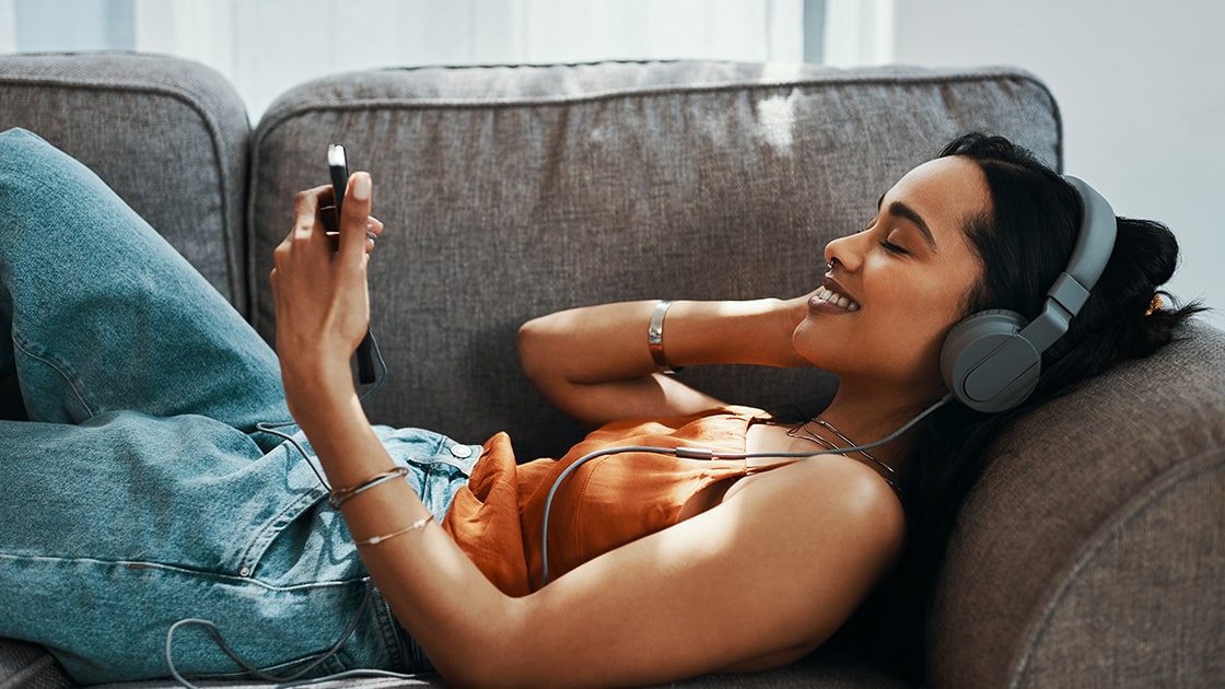 Young woman llstens to music on the couch